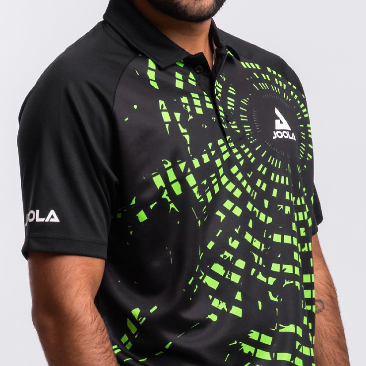 Schwarzes JOOLA Poloshirt mit grünem, pixelartigem Muster, kurzärmlig, getragen von einem Mann.