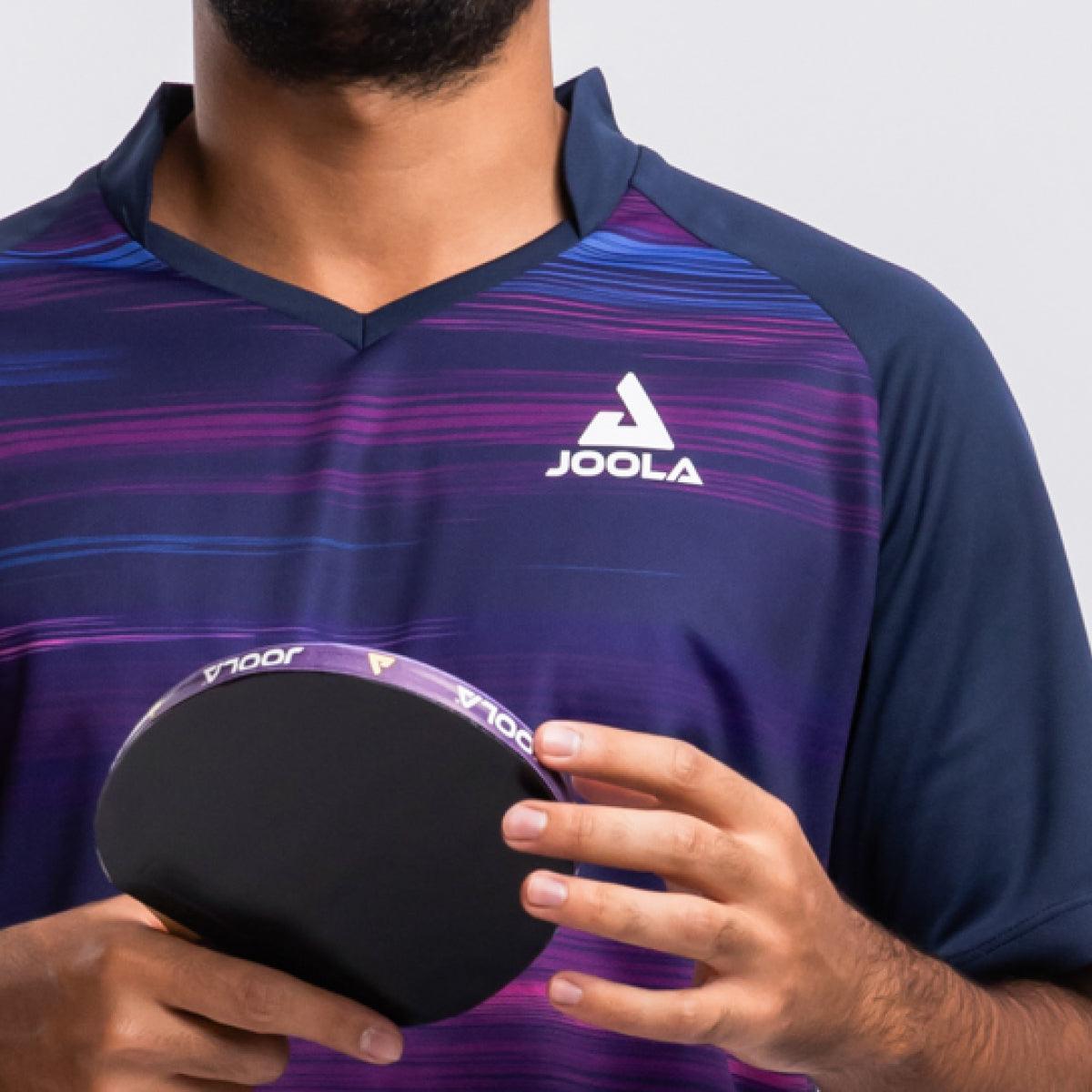 Mann trägt blau-lila JOOLA Tischtennis-Trikot und hält JOOLA Tischtennisschläger.
