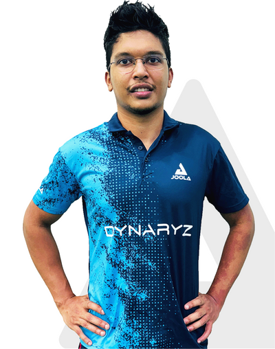 Mann mit Brille trägt blau-schwarzes JOOLA Dynaryz Sportshirt mit kurzem Kragen und Muster auf der linken Seite.