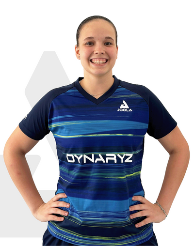 Junge Frau trägt blaues JOOLA Sportshirt mit Dynaryz-Logo, lächelt, Hände in Hüftposition.