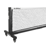 Mobile JOOLA Tischtennis-Netzgarnitur mit schwarzem Netz und weißem Randband auf Rollen, freistehend.
