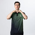 Mann trägt schwarzes Polo-Shirt mit grünem, geometrischem Linienmuster und Logo auf der Brust.