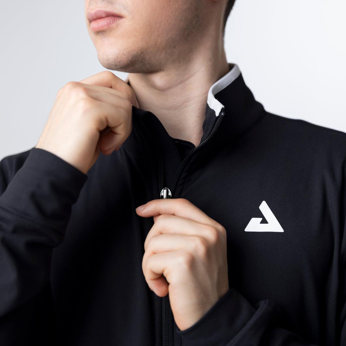 Mann zieht schwarzen Sportpullover mit Reißverschluss und weißem Logo am Brustbereich hoch.